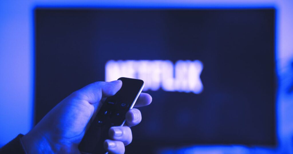 Main tenant une télécommande pour éteindre Netflix