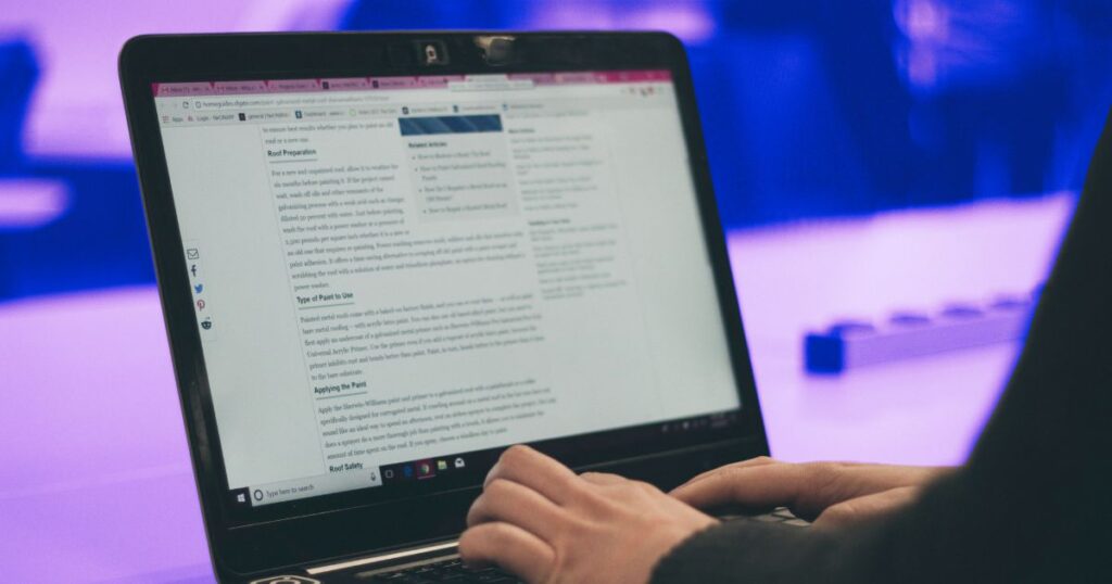 Ecran d'ordinateur et vue sur les mains d'un blogueur en train d'écrire un article