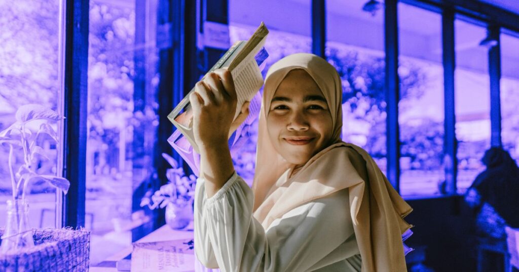 Jeune femme voilée souriante avec un livre à la main