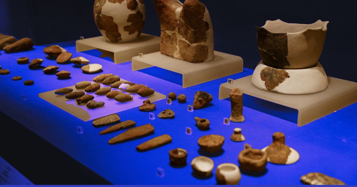 Objets archéologiques du Néolithique : outils en pierre et poteries anciennes exposés dans un musée