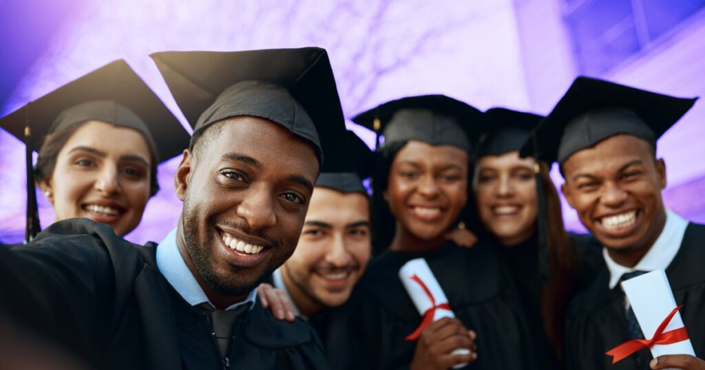 Un groupe de jeunes souriants en tenue de diplômés