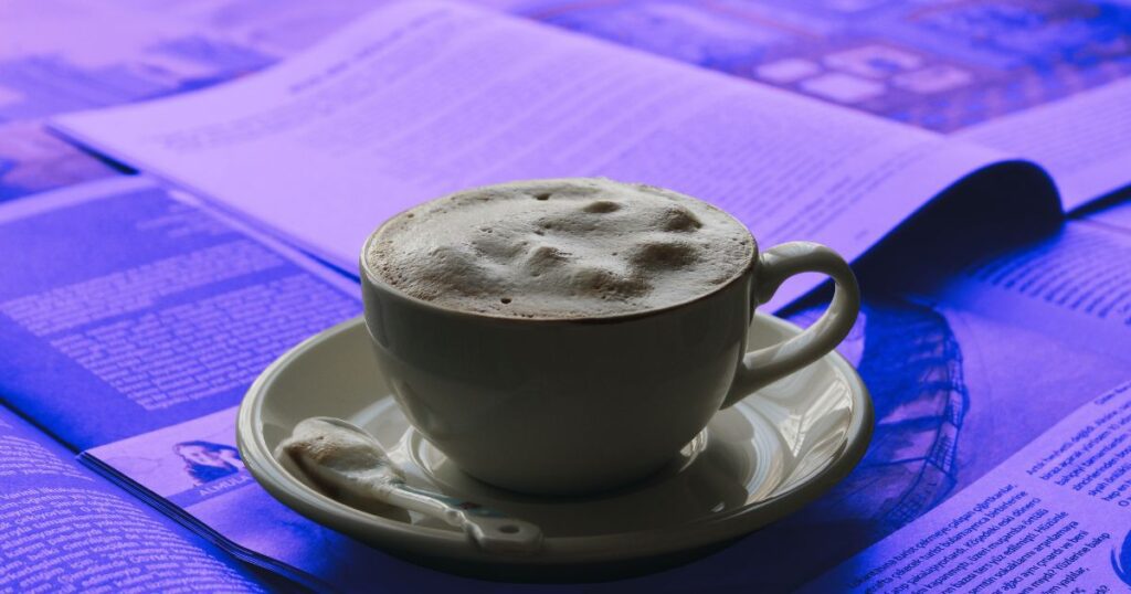 Une tasse de café mousseux sur des journaux pour illustrer le plaisir de commencer à se cultiver