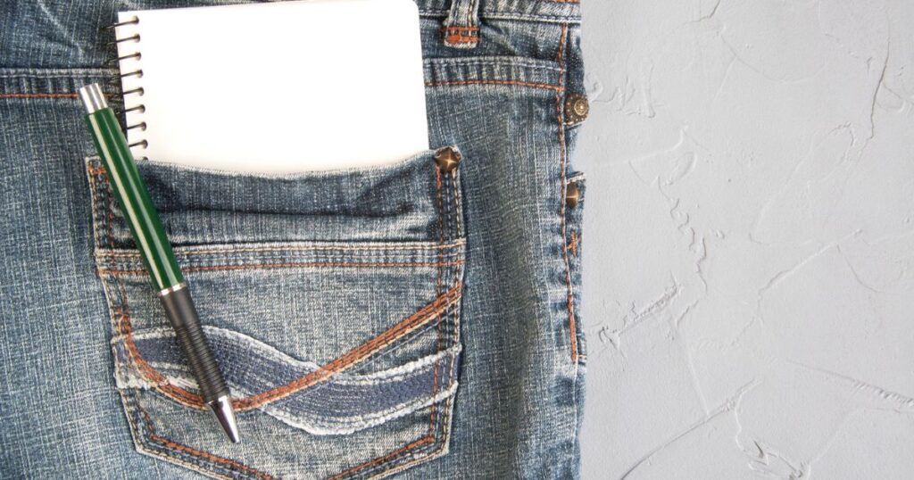 Un carnet et un stylo calés dans la poche arrière d'un jean