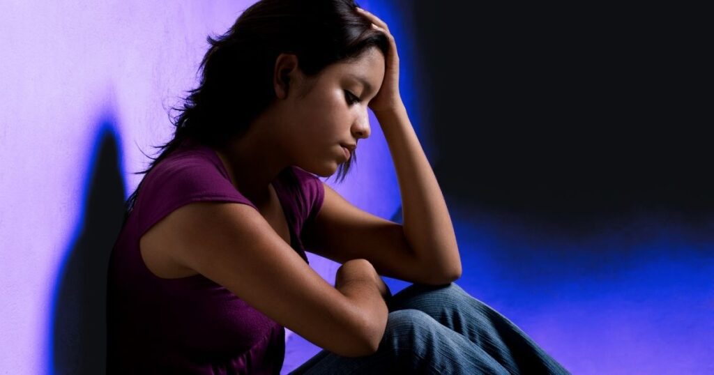 Jeune femme assiste par terre et soucieuse, ayant peur d'être bête