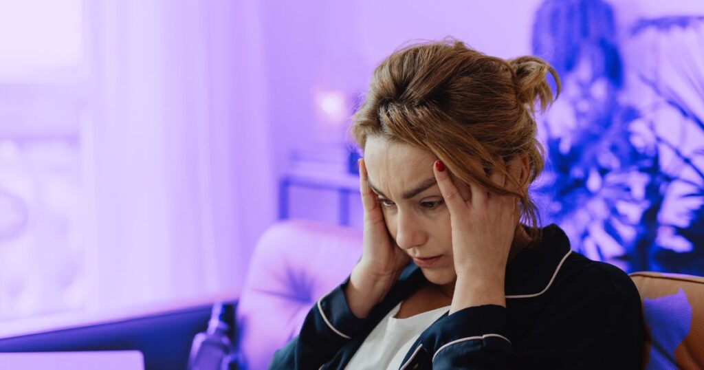 Une femme se tient les tempes, anxieuse et victime des biais à l'oeuvre dans les actus