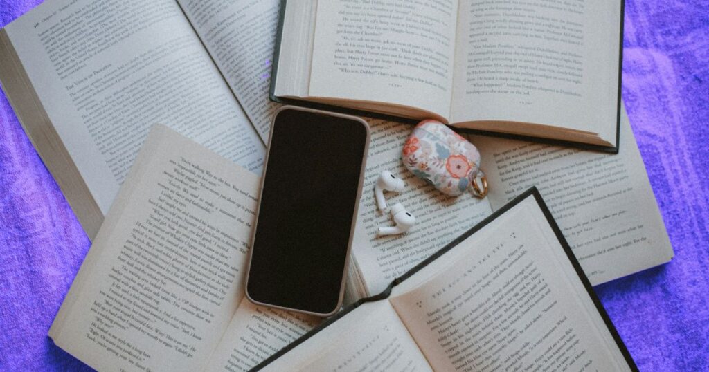 Plusieurs livres et un smartphone posées sur une table pour améliorer sa culture générale en reliant les domaines entre eux