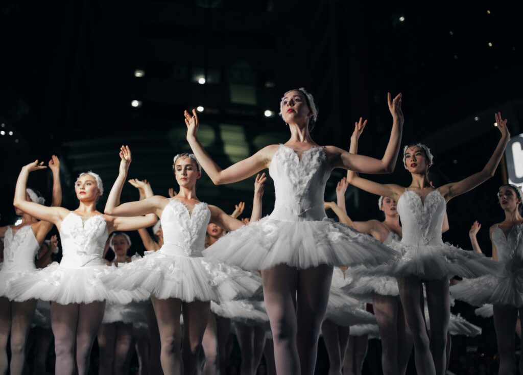 Un groupe de danseuses étoiles en tutu blanc évoluent sur scène, illustrant l'art du ballet.