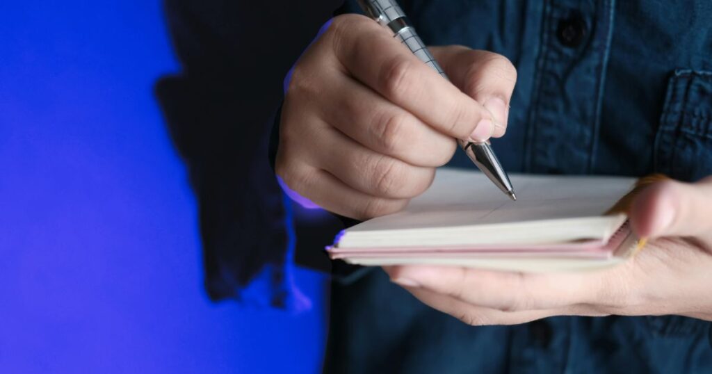 Une main écrit au stylo dans un carnet pour ancrer un apprentissage