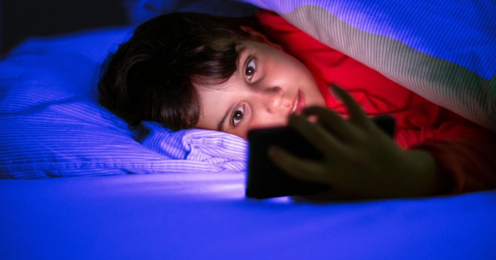 Un ado consulte son smartphone dans son lit