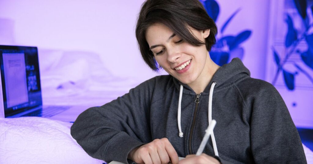 Une jeune femme souriante et détendu se cultive avec un stylo en main