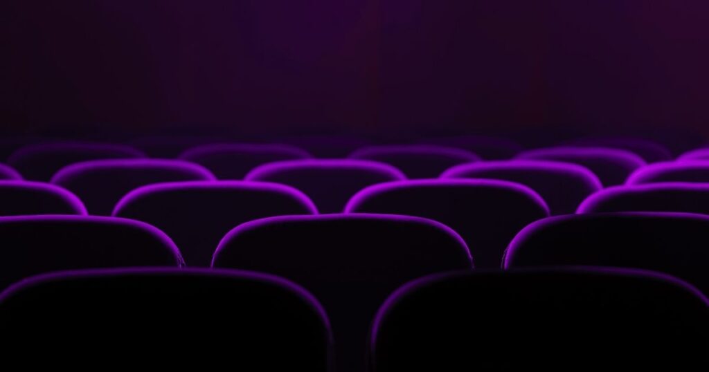 Gros plans sur des fauteuils de cinéma dans une salle obscure
