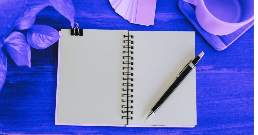 Un carnet, un stylo et un café sur une table, illustrant la démarche de retenir ce qu'on lit
