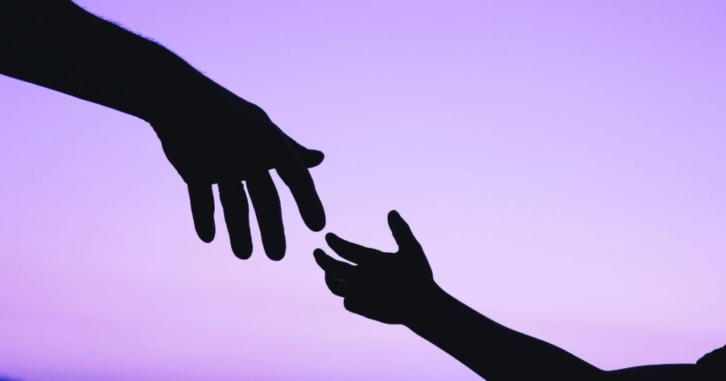 Une main d'adulte se tend pour prendre la main d'un enfant